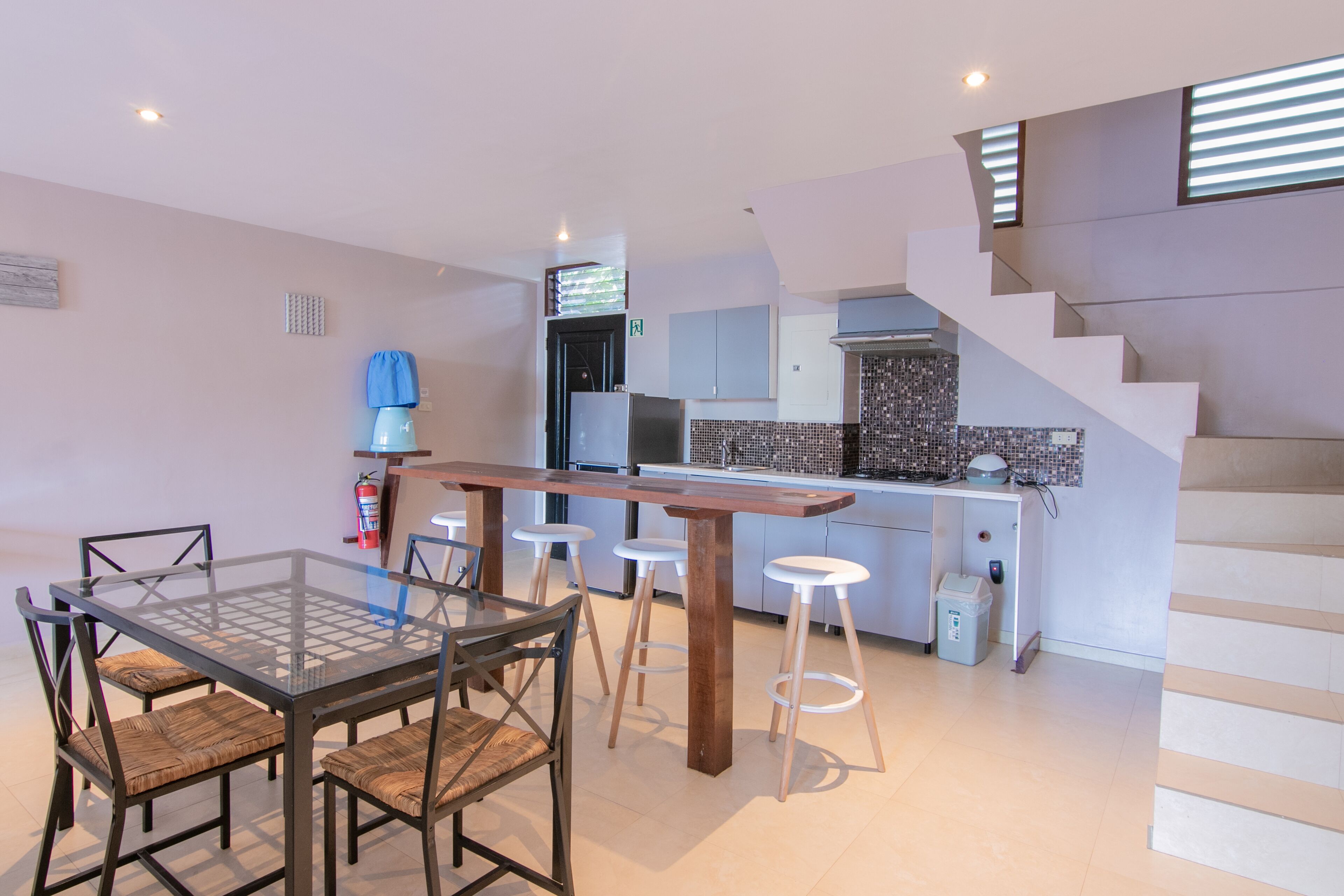A modern kitchen with a central island, bar stools, and a dining table with chairs.