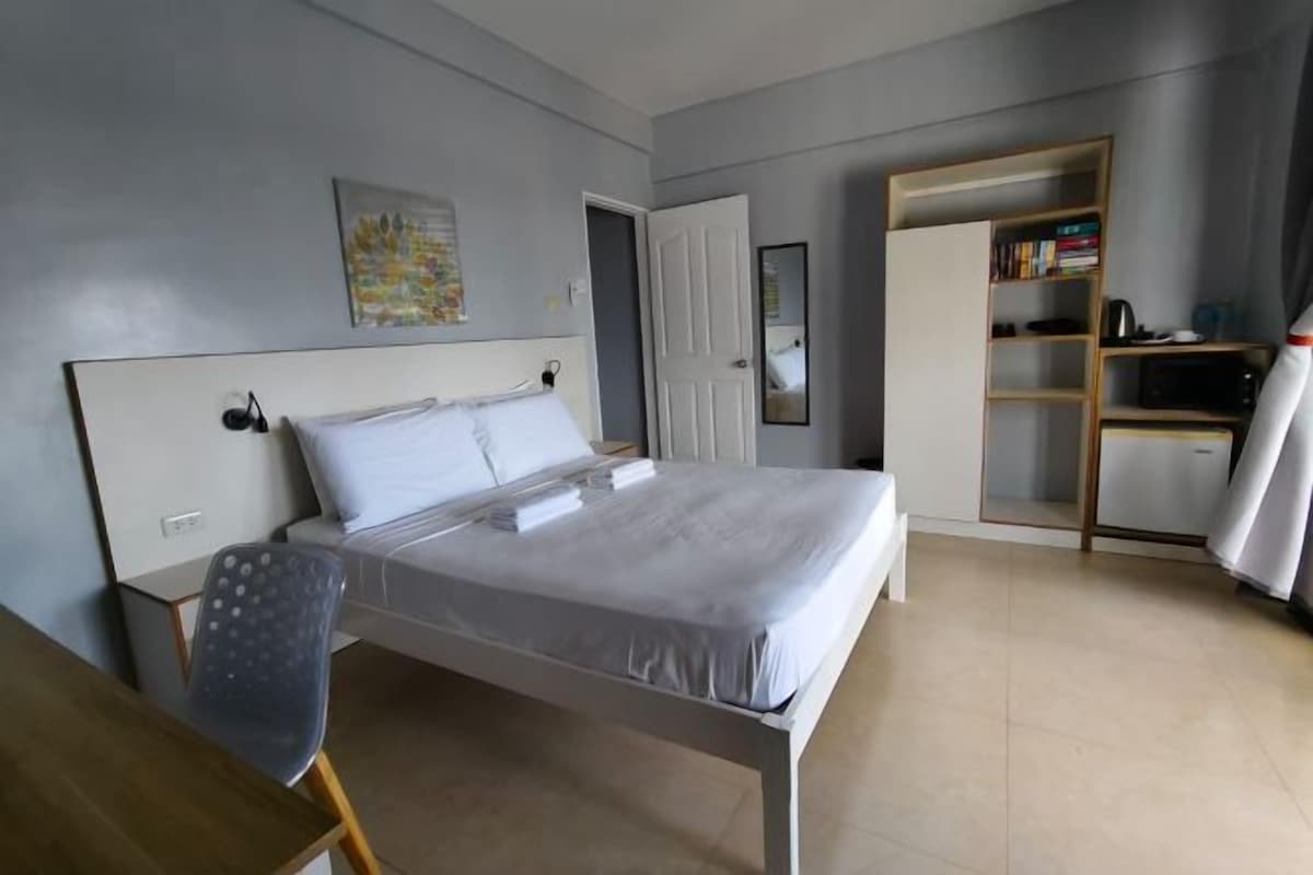 Un dormitorio ordenado con cama, escritorio y estantería.