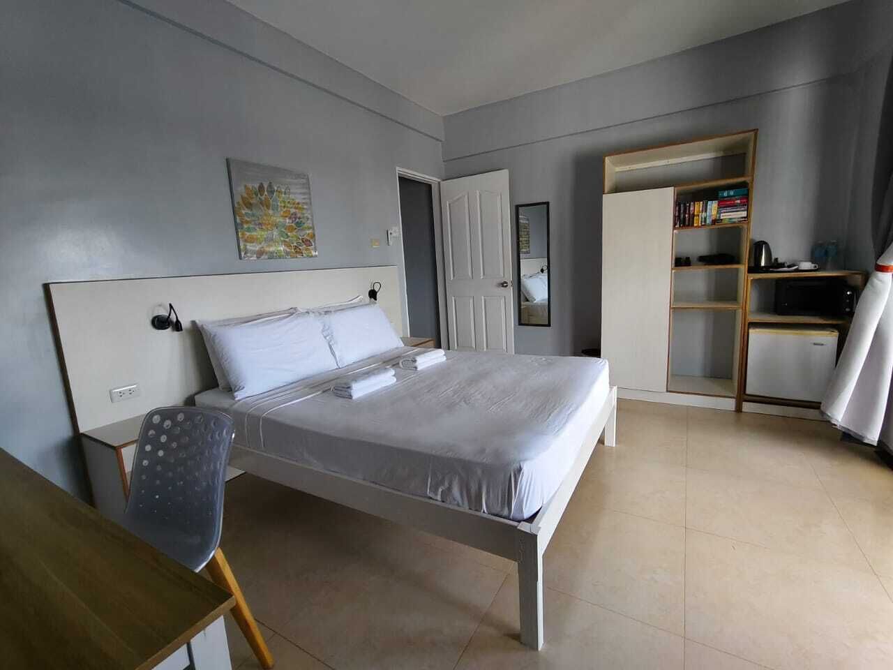 Ein Schlafzimmer mit Bett, Stuhl, Bücherregal und Tür.