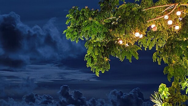 A night scene with a moonlit beach, two bean bags, a small table, and string lights. - Reef Beach Resort (General Luna)