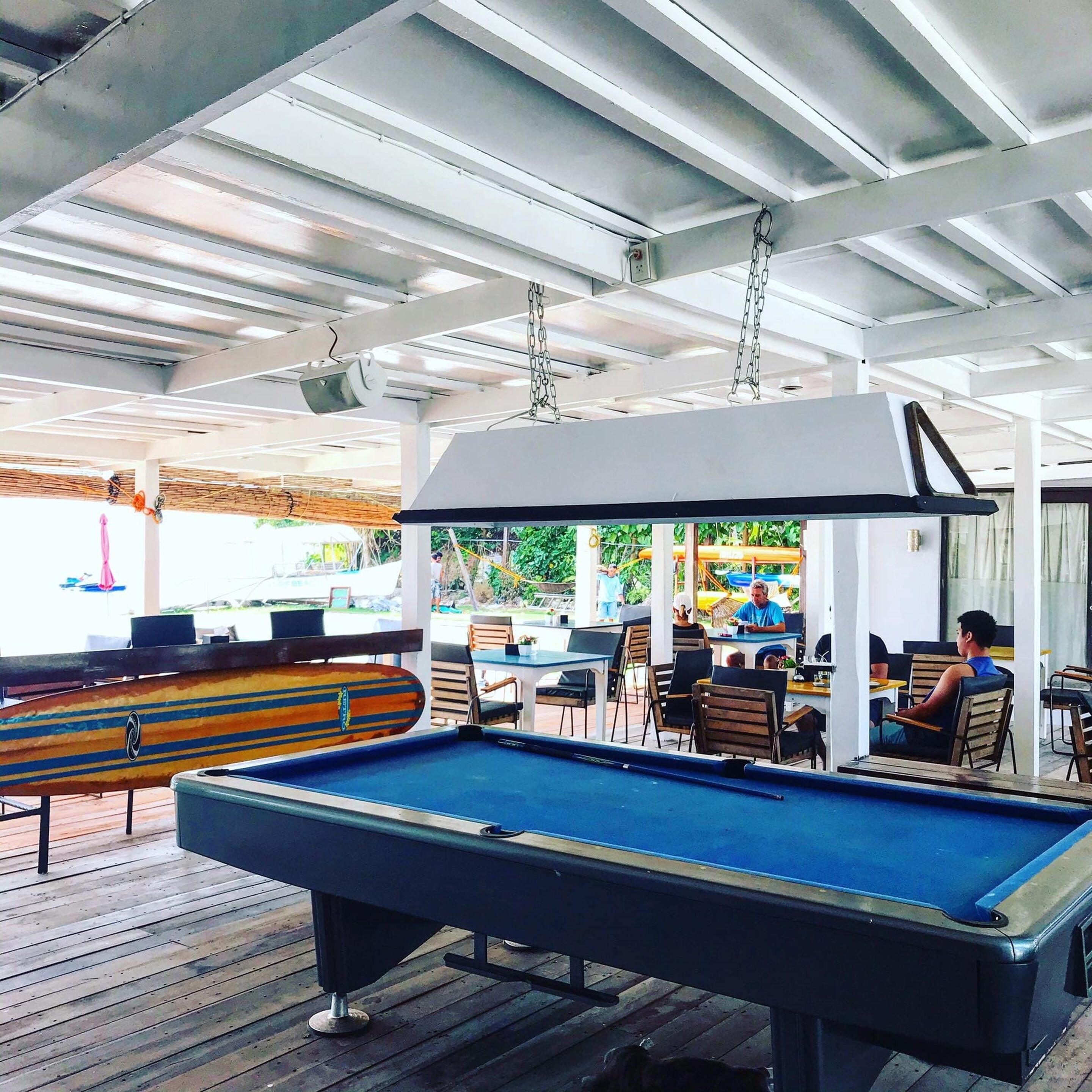 An outdoor pool area with a pool table, chairs, and tables.