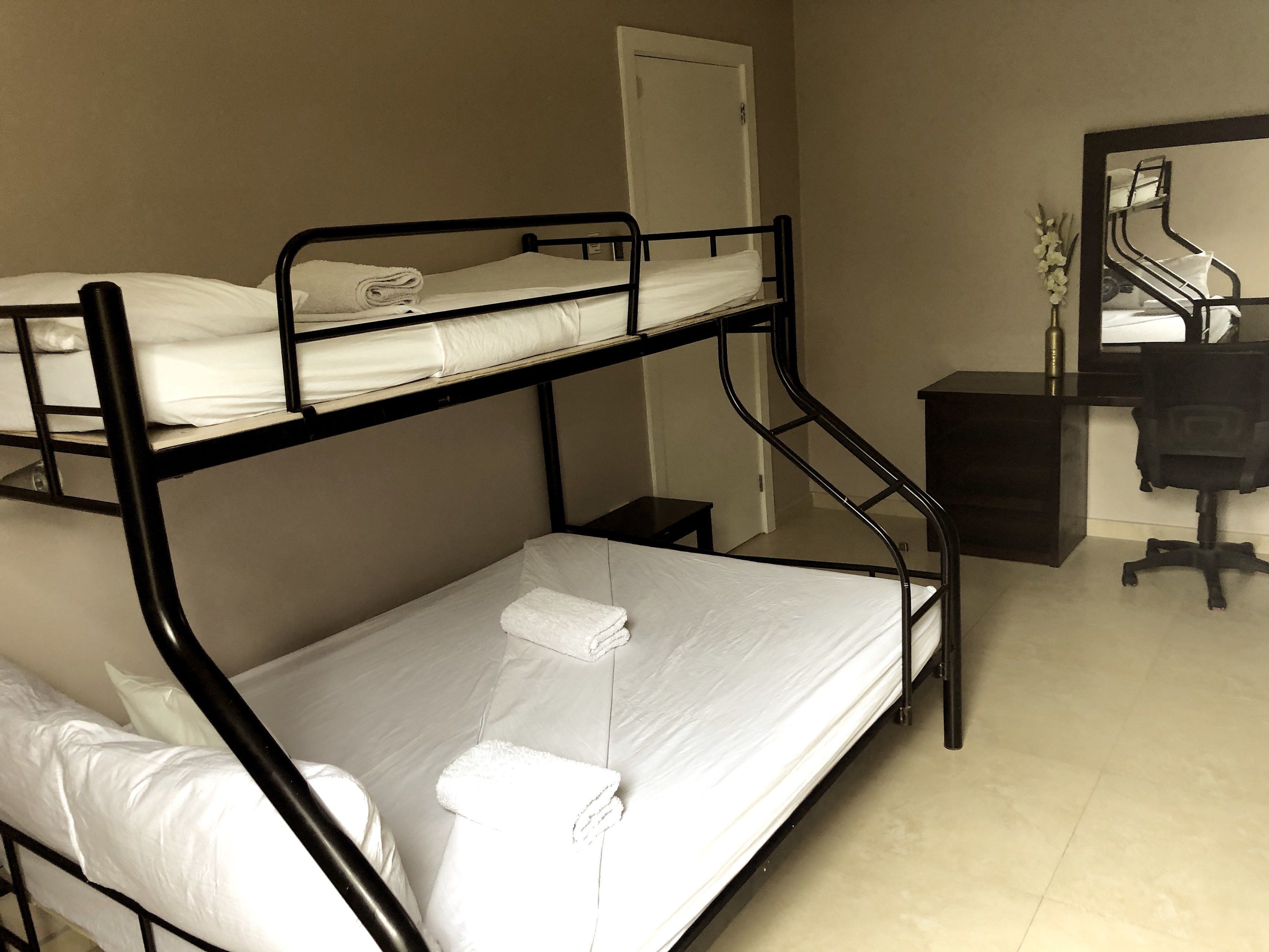 Camera con letto a castello, scrivania, sedia, uno specchio e un piccolo armadio.
