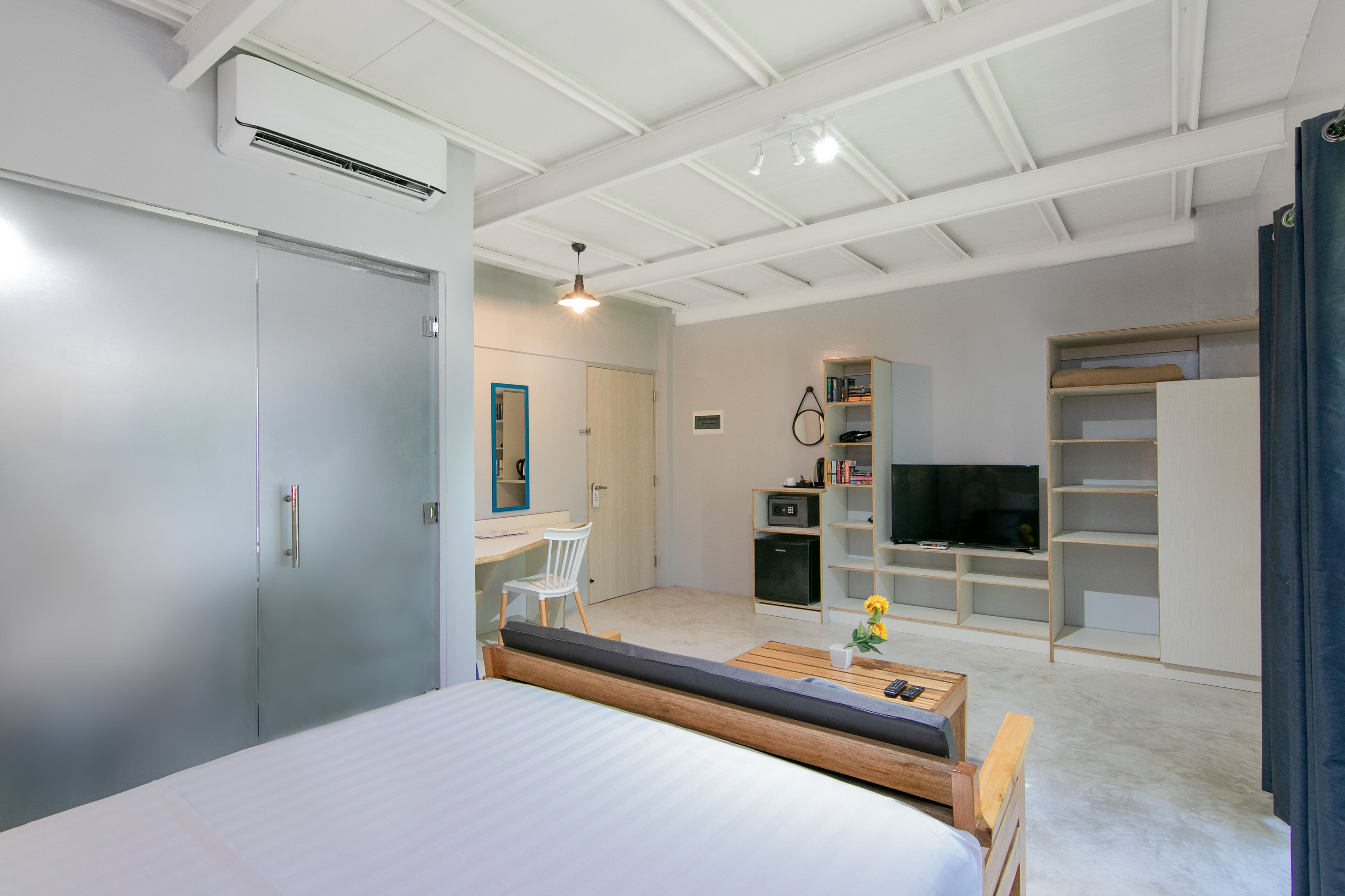 Un dormitorio moderno con cama, escritorio, televisor y armario.