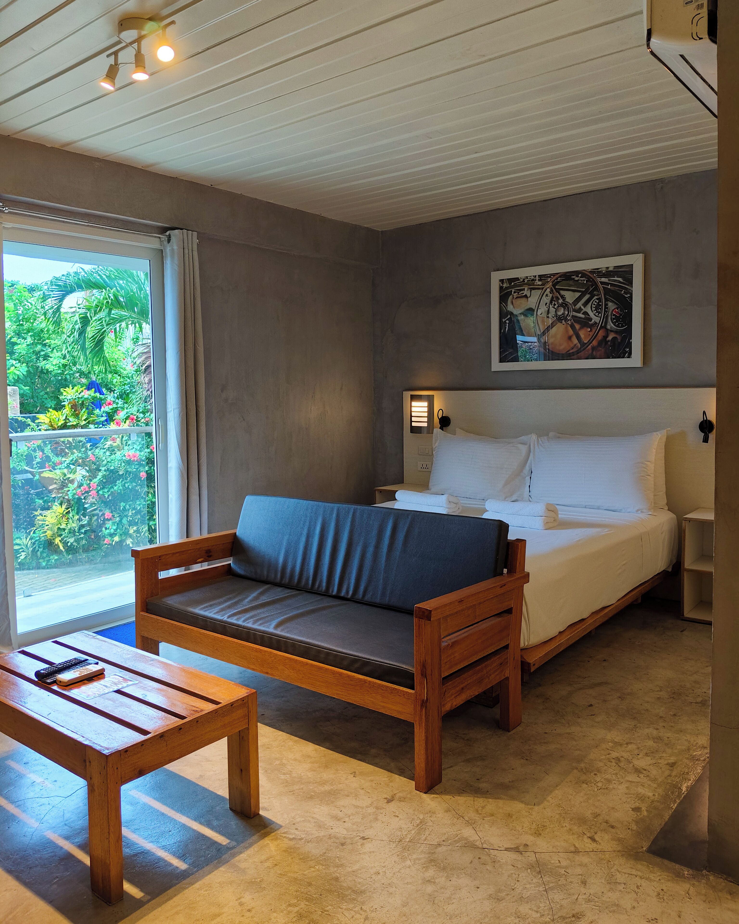 Una habitación con cama, sofá, mesa de madera y vistas al exterior.