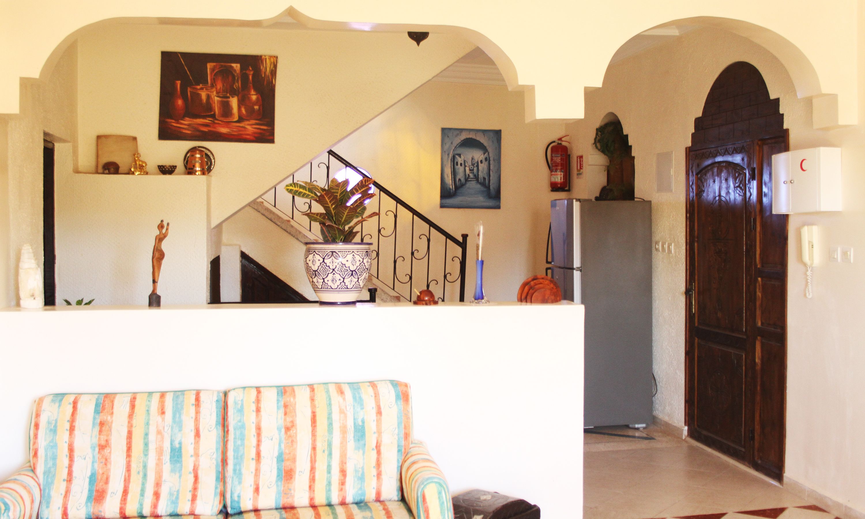 A living room with a sofa, a staircase, and a door leading to another room.