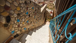 A stone staircase with colorful pebbles, leading to a balcony with a blue railing overlooking a cityscape. - Original Surf Morocco - Hostel (Aourir)