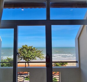 A window with a view of the ocean and a tree. - HaiDuong Intourco Resort (Vung Tau)