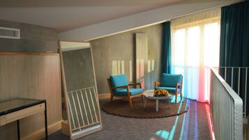 A room with a large mirror, two blue chairs, a small table with a vase, and a view of the outside through large windows.