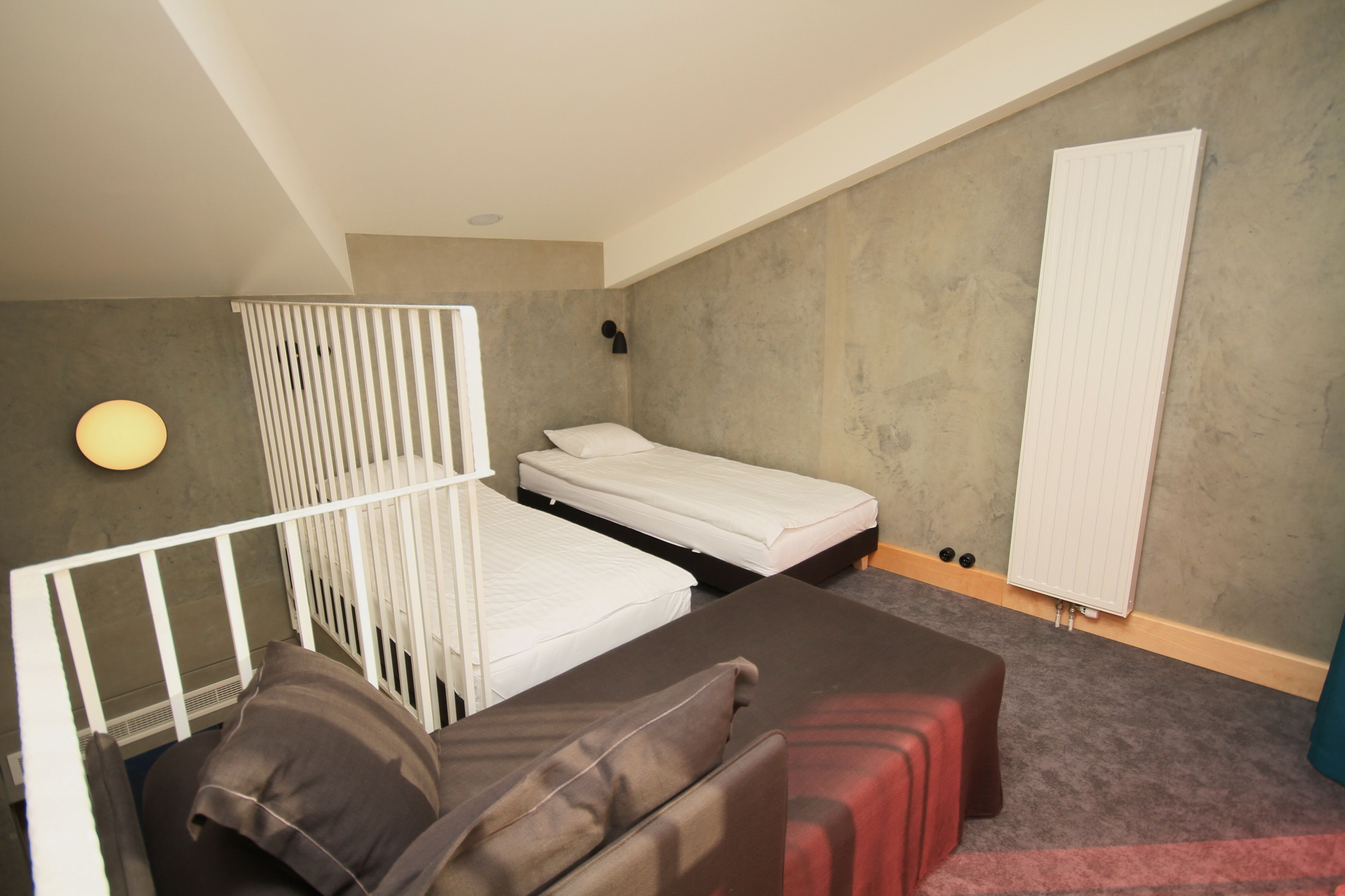 A room with two single beds, a sofa, and a radiator.