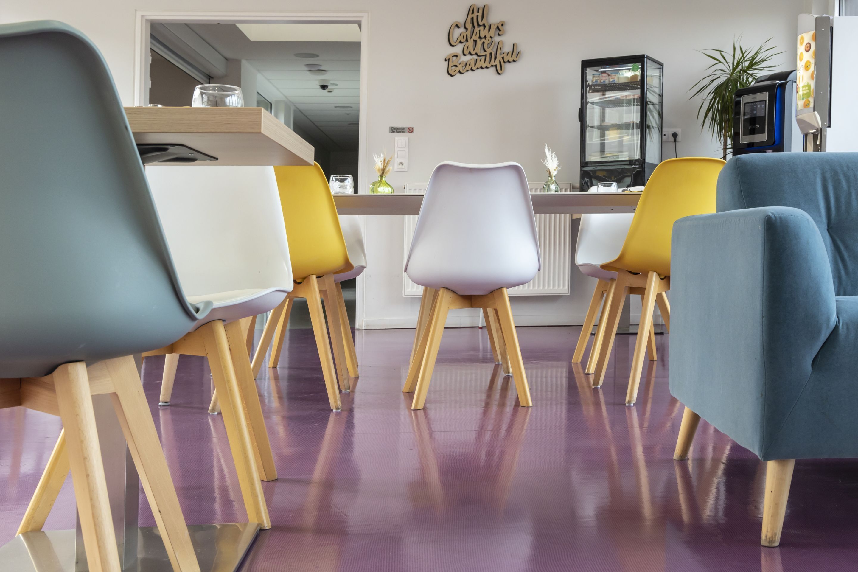 Un comedor con piso morado, sillas de madera y una mesa blanca.
