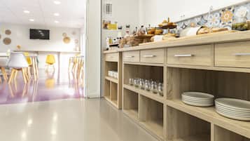 Una cocina moderna con armarios de madera, una encimera con pan y condimentos, y un comedor con sillas y una mesa.