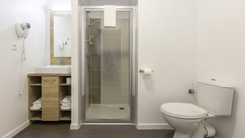 A modern bathroom with a glass-enclosed shower, a white toilet, and a wooden vanity with a towel rack.