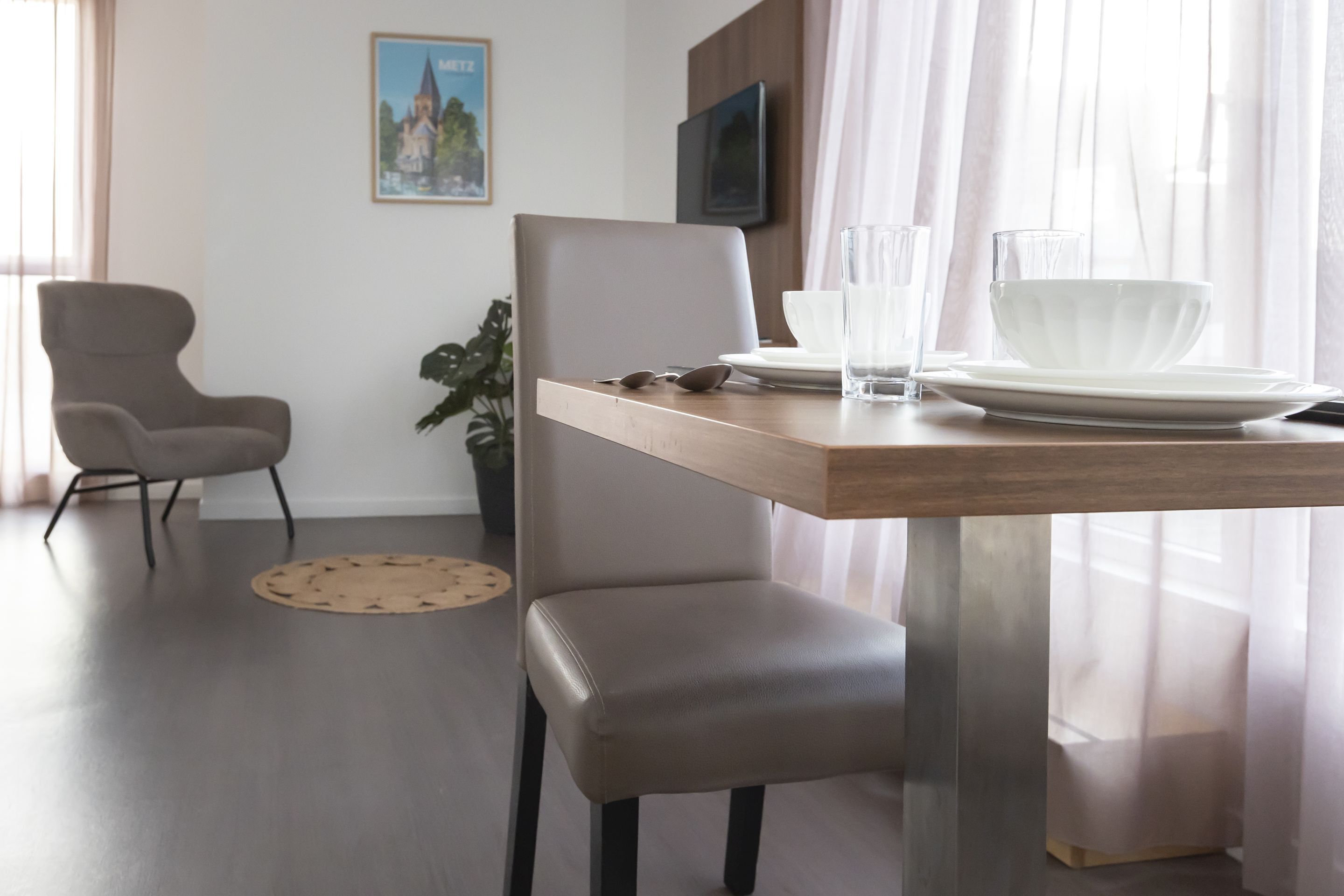A modern dining area with a wooden table, a grey upholstered chair, and a potted plant.