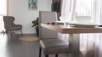 A modern dining area with a wooden table, a grey upholstered chair, and a potted plant.