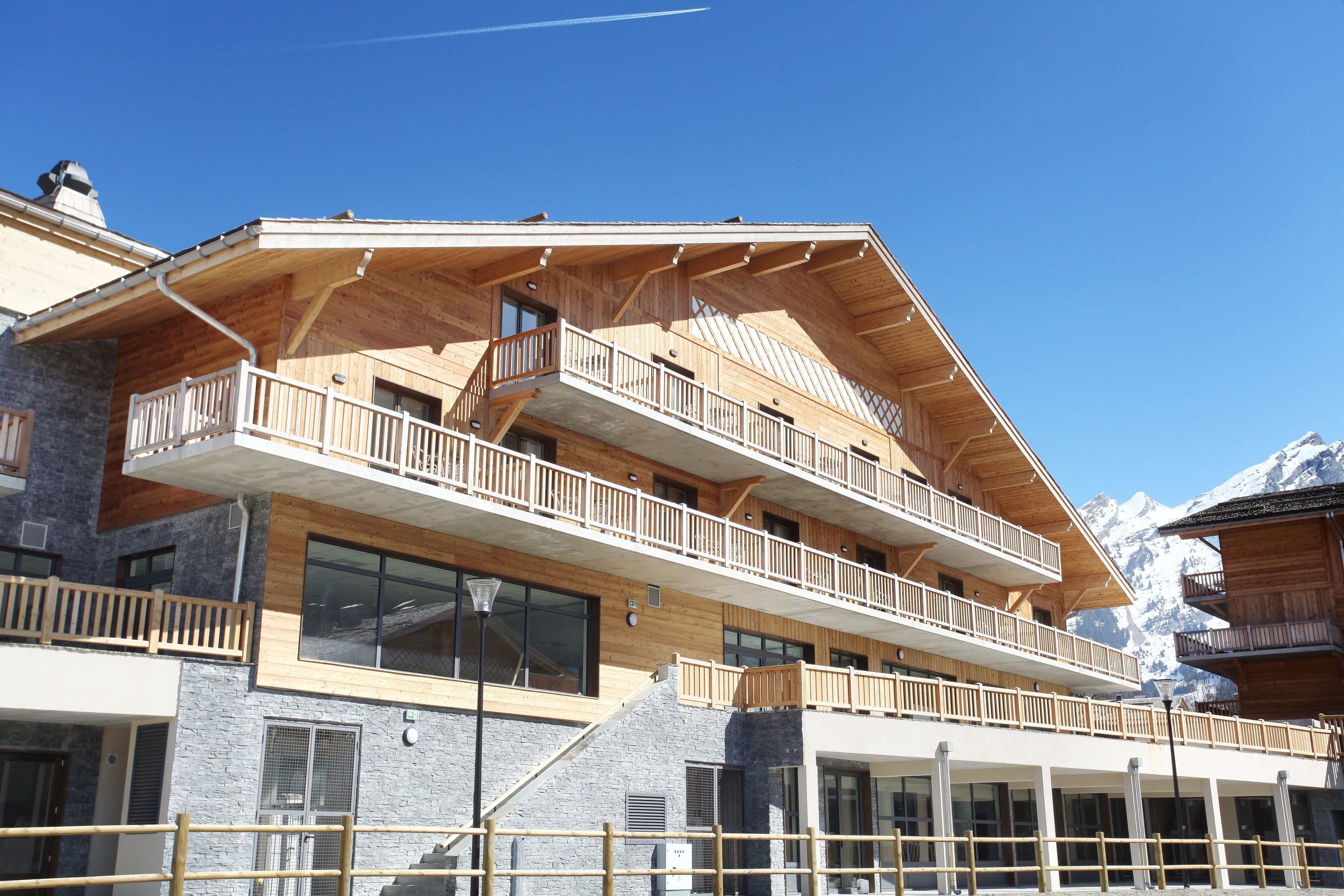 Un edificio de madera de varios pisos con balcones, ventanas amplias y fachada de piedra.