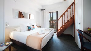 Ein Hotelzimmer mit einem Bett, einem Spiegel, einer Treppe und Blick nach draußen.
