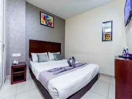 Ein Hotelzimmer mit einem Bett, einem Nachttisch, einem an der Wand montierten Fernseher, einem Spiegel und einem Gemälde.