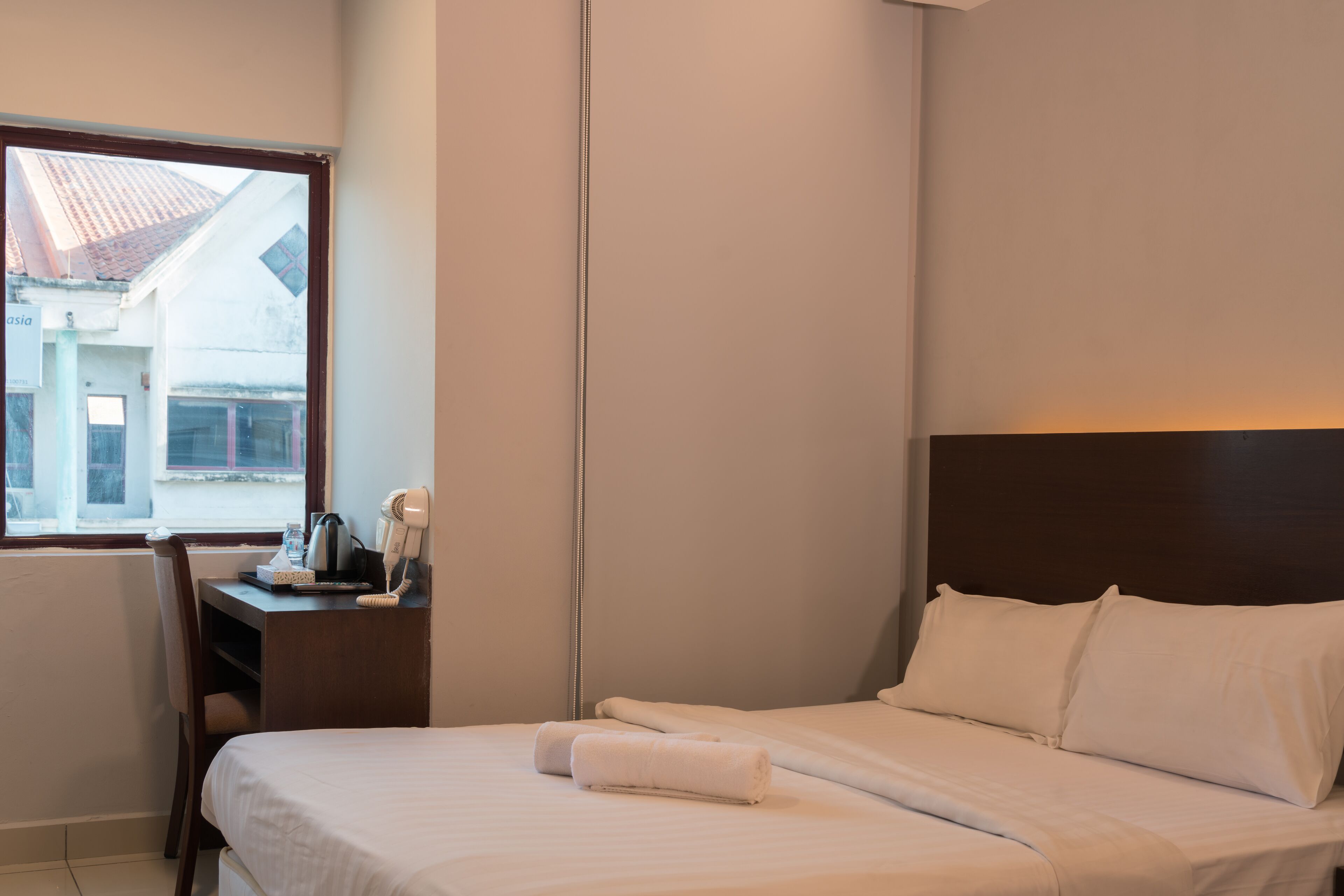 Una habitación de hotel con una cama, un escritorio y un teléfono, y una ventana.