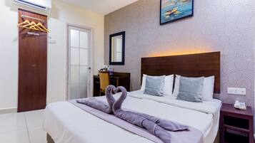 A hotel room with a bed, a wooden headboard, a painting on the wall, and a wardrobe with hangers.
