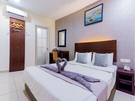 A hotel room with a bed, a wooden headboard, a painting on the wall, and a wardrobe with hangers.