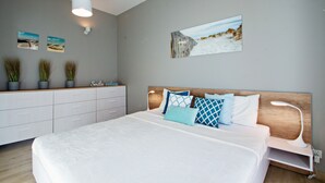 Un dormitorio moderno con una cama grande, mesitas de noche, un aparador y una obra de arte en la pared.