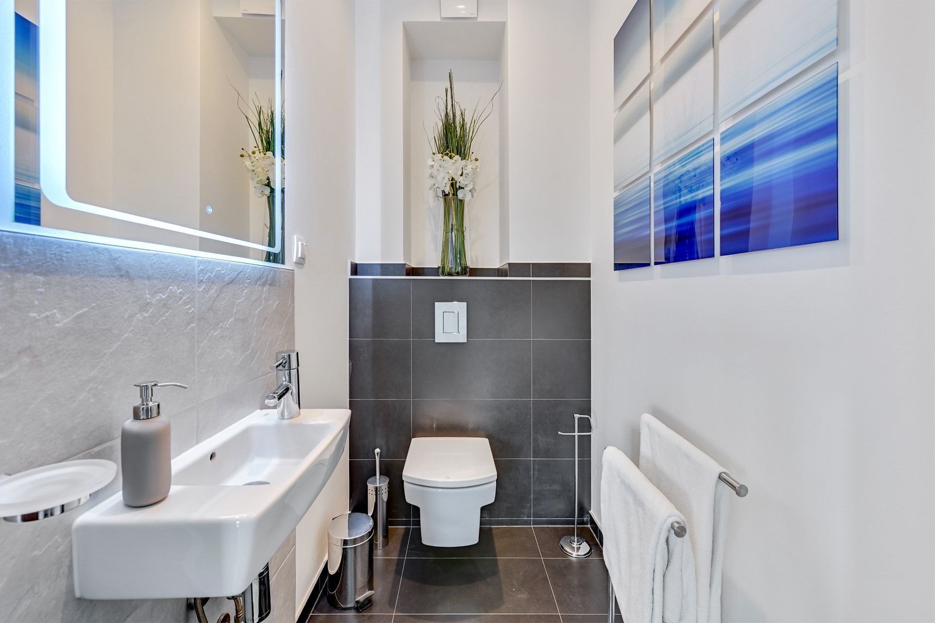 A modern bathroom with a sink, toilet, and a mirror.