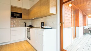 Una cocina moderna con muebles blancos, un microondas integrado y una cafetera sobre la encimera.