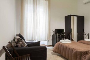 Una camera da letto con un letto, una sedia, un armadio e una finestra con tende.