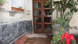 A building entrance with a wooden door, a potted plant, and a street lamp. - B&B Tra L'Etna e il Mare (Catania)