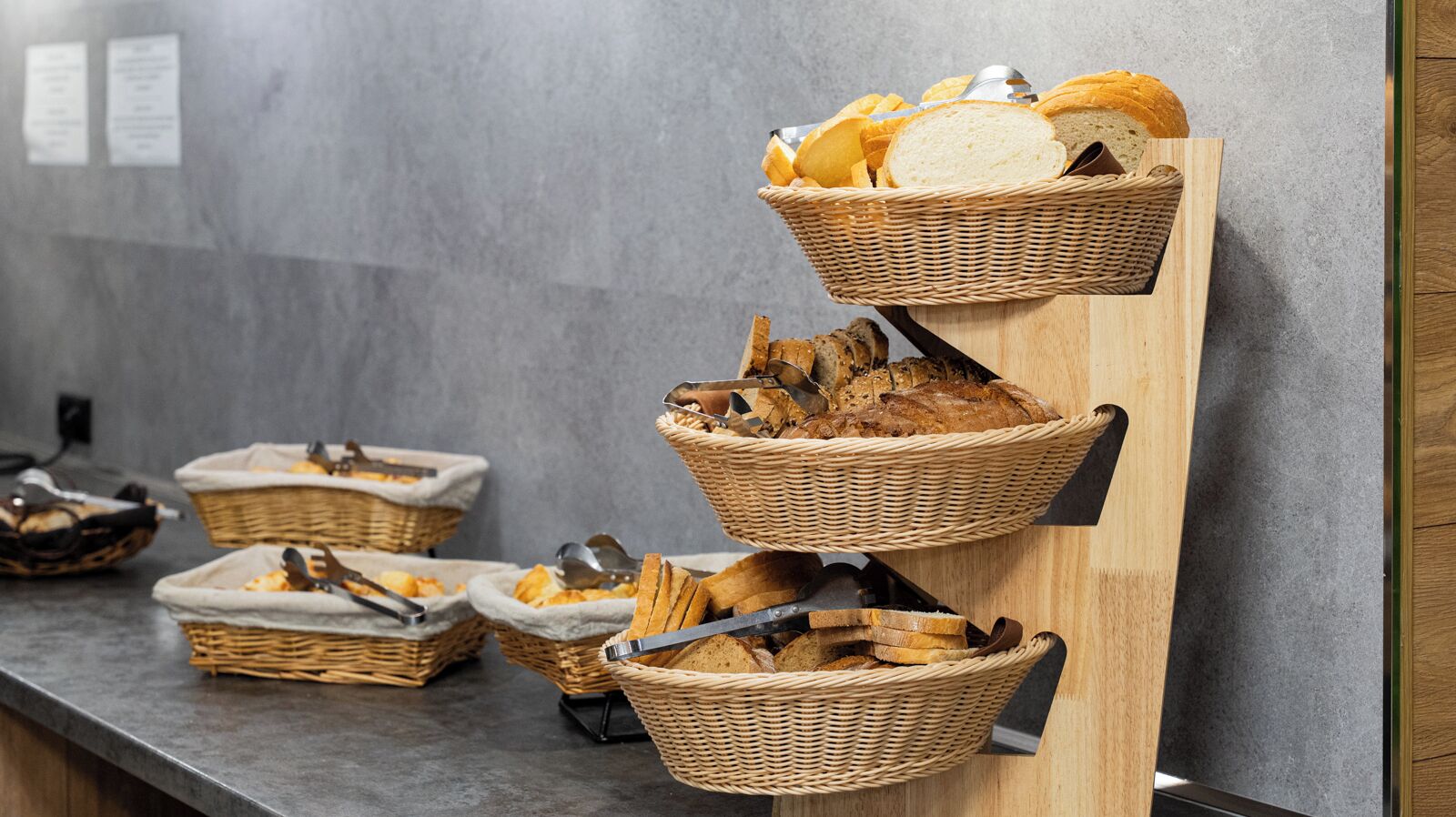 A buffet setup with multiple wicker baskets containing bread and utensils.
