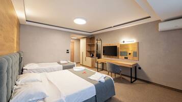 Ein Hotelzimmer mit zwei Betten, einem Schreibtisch, einem Sessel, einem Fernseher und einem Spiegel.