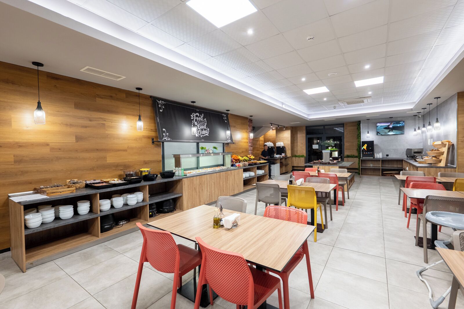 A modern restaurant with wooden walls, a blackboard menu, and a variety of seating options including tables and chairs.