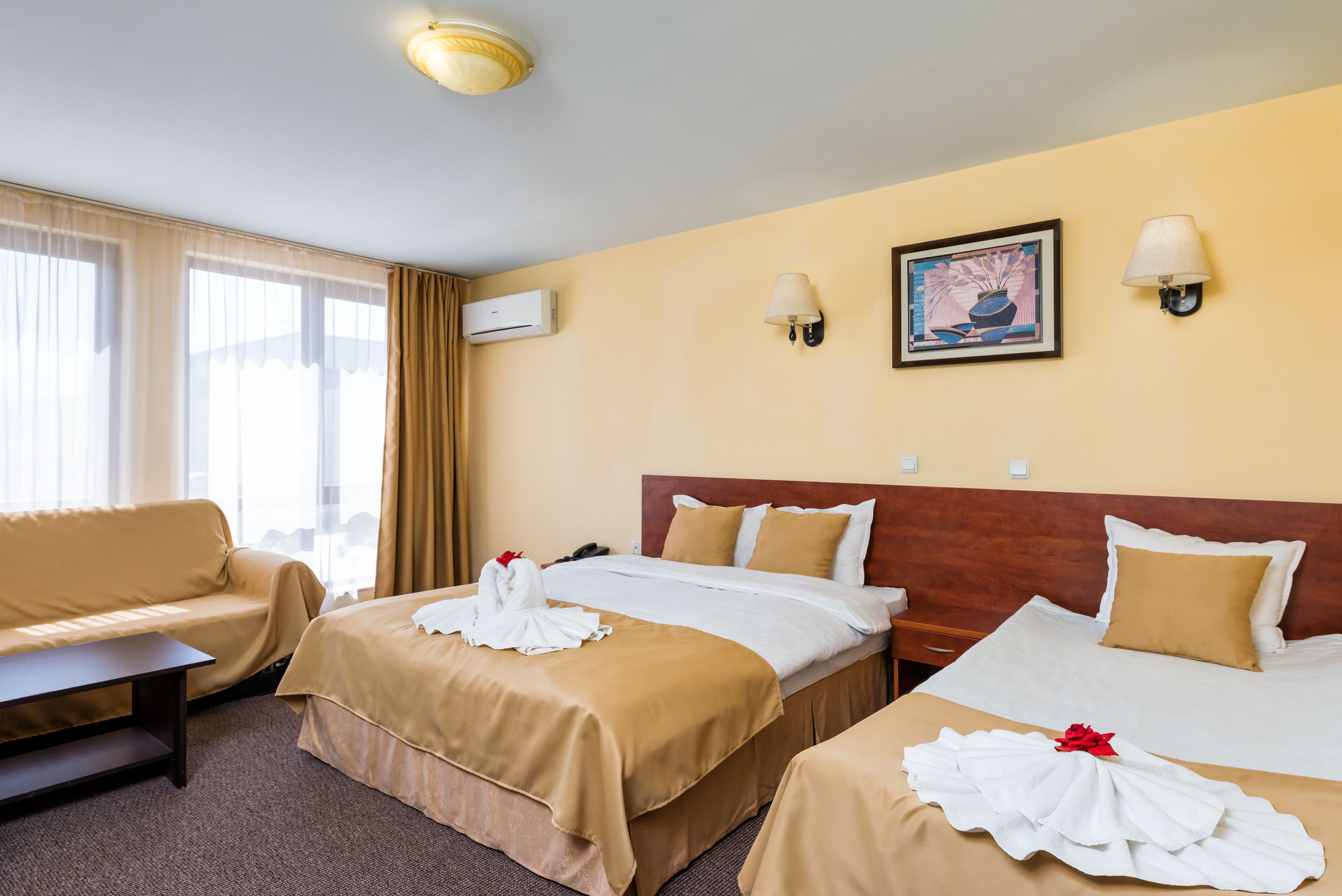 Una habitación de hotel con dos camas, un sofá, un escritorio y un cuadro en la pared.