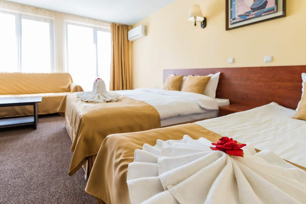Ein Hotelzimmer mit zwei Betten, einer Couch und einem großen Fenster.
