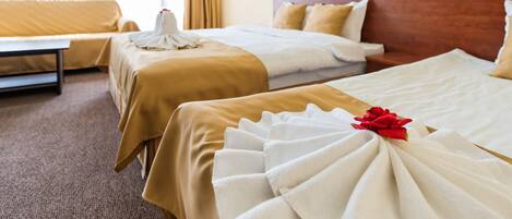 Habitación de hotel con dos camas, un sofá y un ventanal grande.