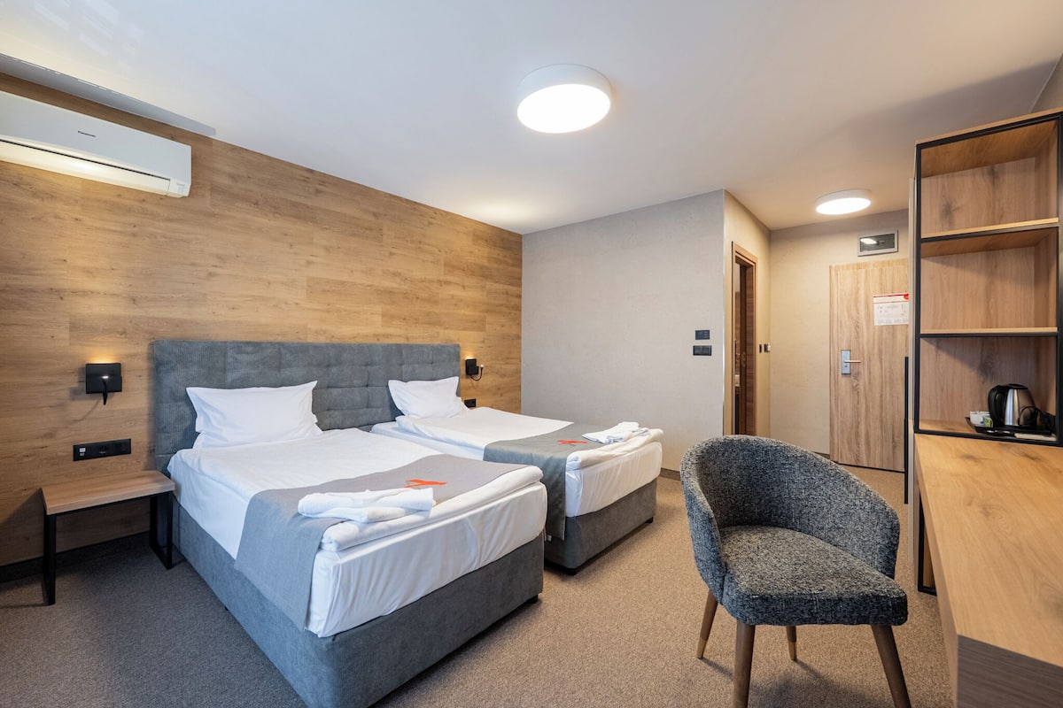 Ein Hotelzimmer mit zwei Betten, einem Schreibtisch, einem Stuhl und einem Kleiderschrank.