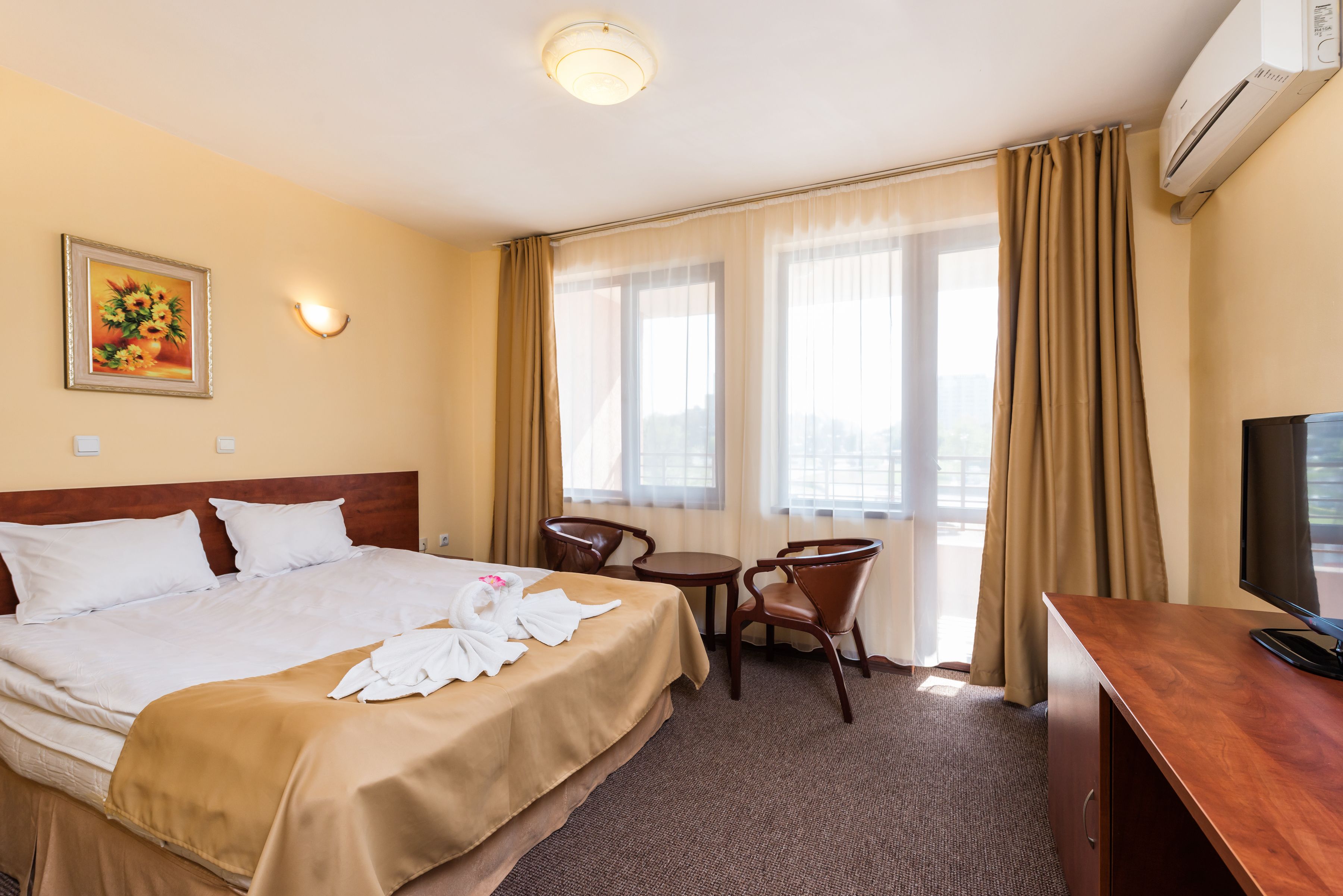 A hotel room with a bed, a desk, a chair, a television, and a window with curtains.