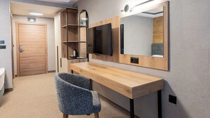 Een moderne kamer met een houten bureau, een stoel, een televisie en een grote spiegel.