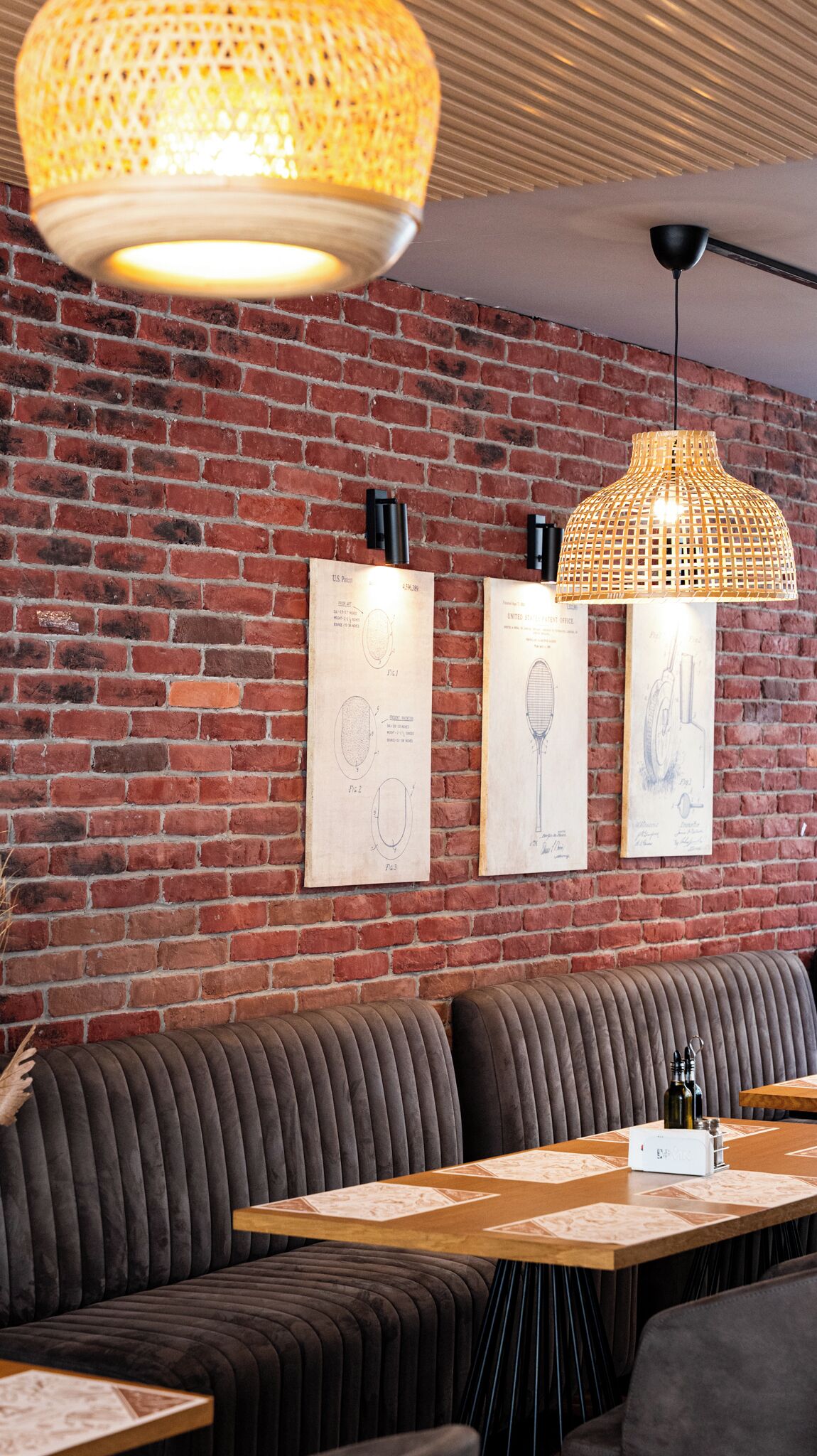 Ein Restaurant mit Backsteinwand, Holztisch und gepolsterten Sitzgelegenheiten.