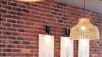 A restaurant with a brick wall, wooden table, and cushioned seating.