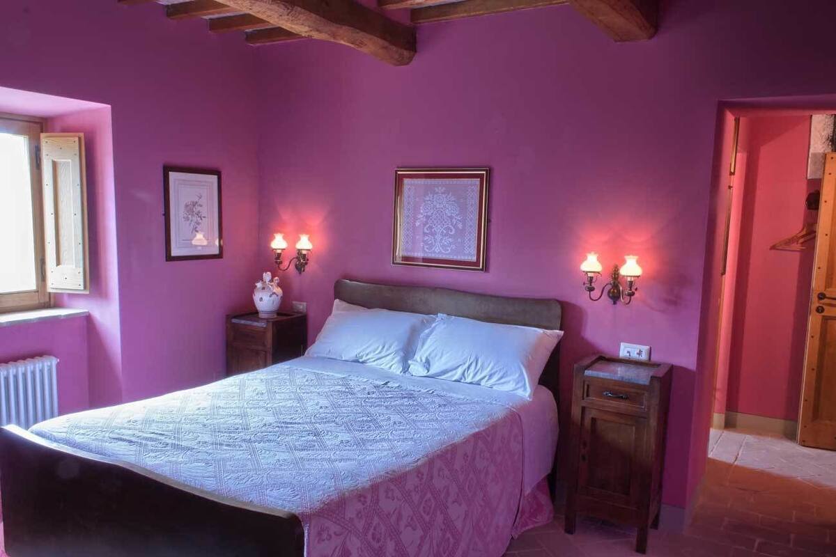 A bedroom with a bed, two bedside tables, and wall-mounted lamps.