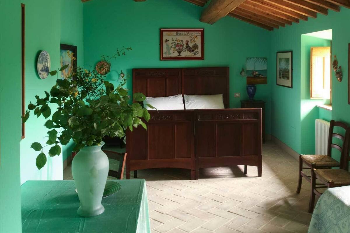 A room with a wooden bed, a green wall, and a wooden ceiling.
