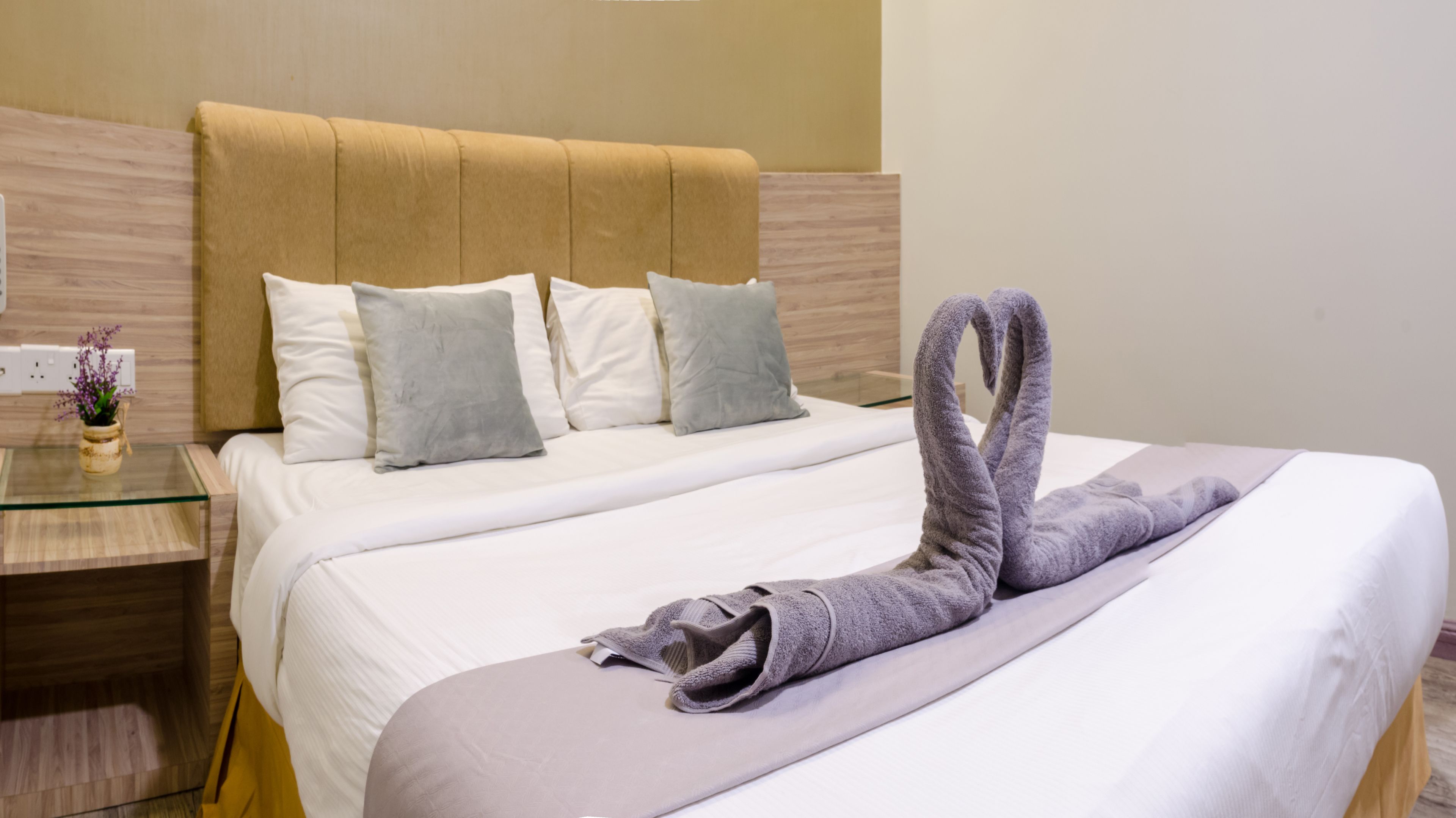 Una habitación de hotel con una cama, una mesita de noche y un jarrón con flores.