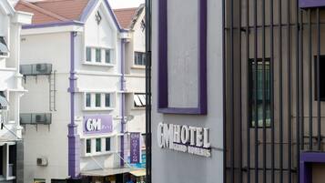 A hotel with a prominent sign, a gated entrance, and a neighboring building with a similar architectural style.