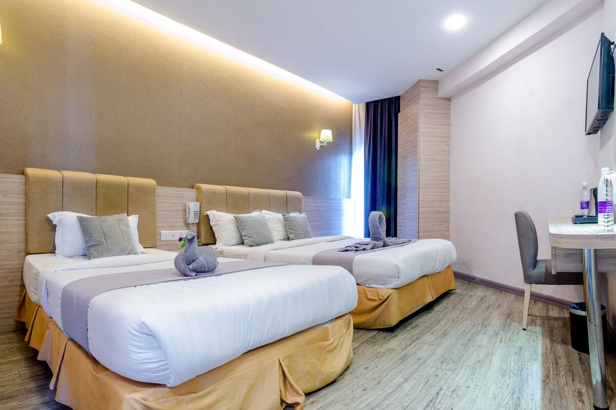 Ein Hotelzimmer mit zwei Betten, einem Schreibtisch und einem Stuhl.