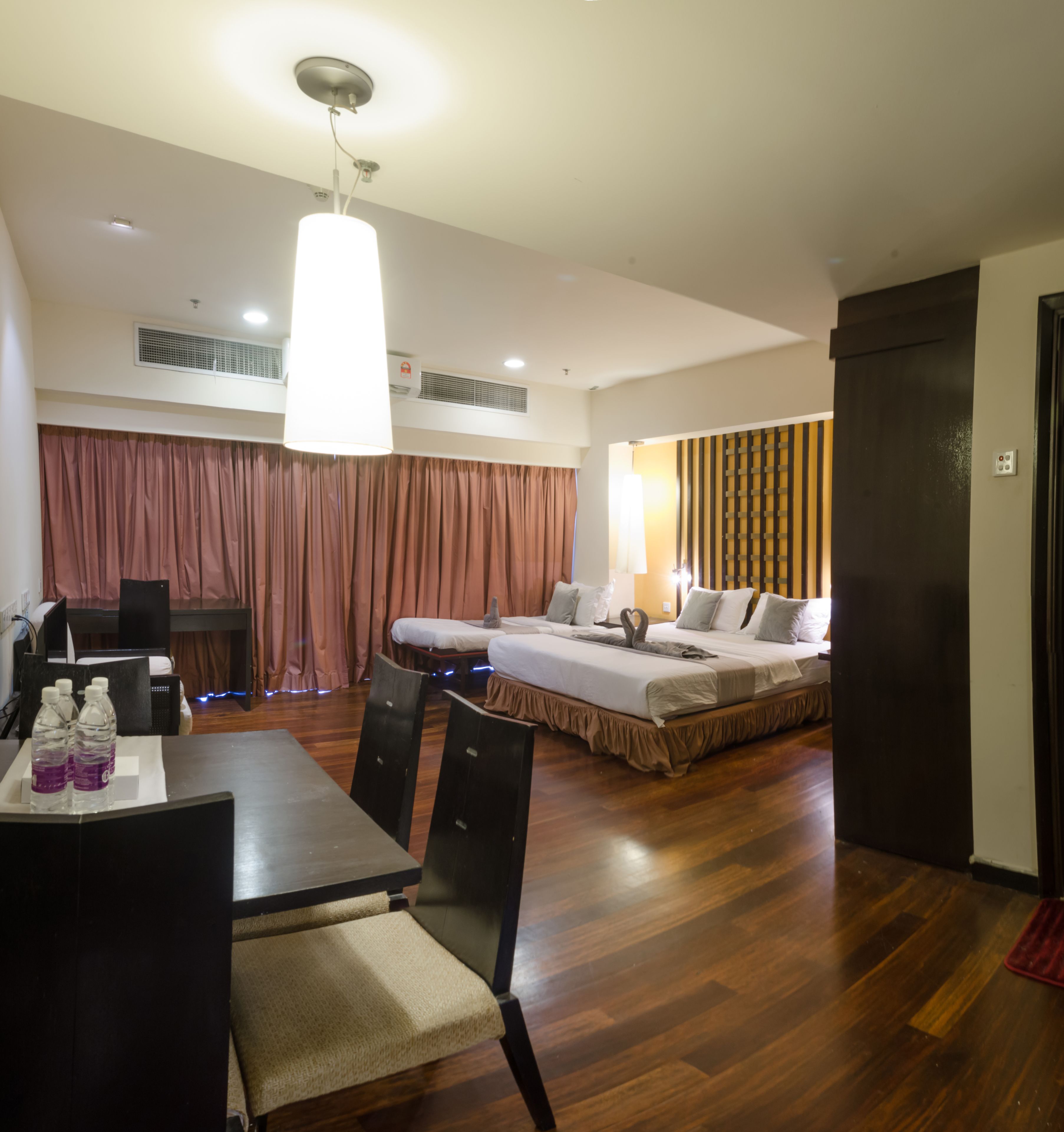 A hotel room with a dining area, two beds, a table with chairs, and a large window.