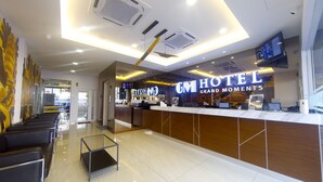 Een hotel receptie met een modern ontwerp, inclusief een receptiebalie, zithoek en een groot digitaal scherm.