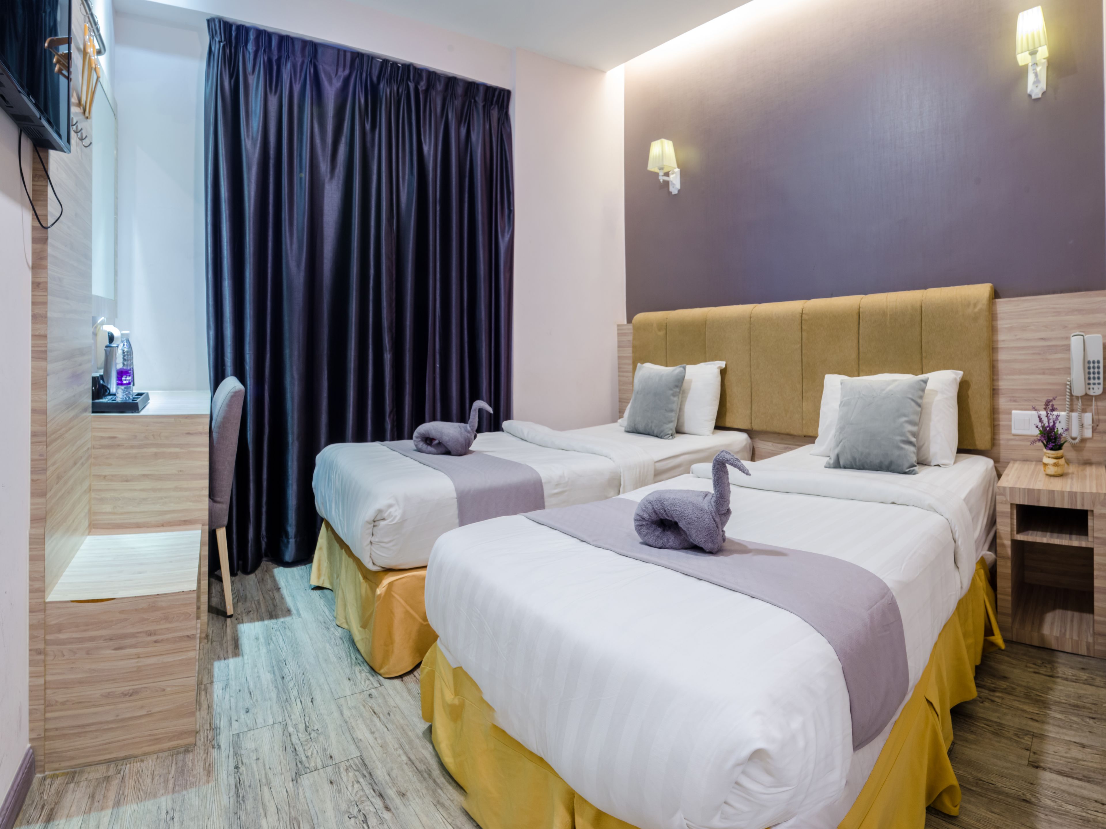 A hotel room with two beds, a desk, a chair, and a curtain.
