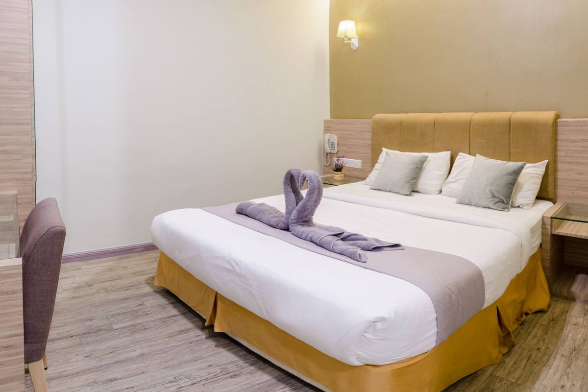 Ein Hotelzimmer mit einem Bett, einem Nachttisch mit Telefon, einem Sessel und einer Wandlampe.