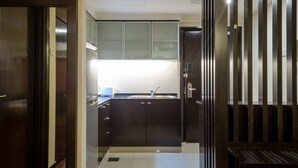 Een moderne keuken met donkere kastjes, een roestvrijstalen spoelbak en een heldere overheadlamp.